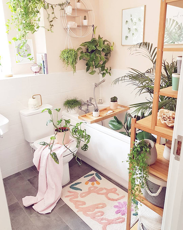 Un baño rosa con muchas plantas