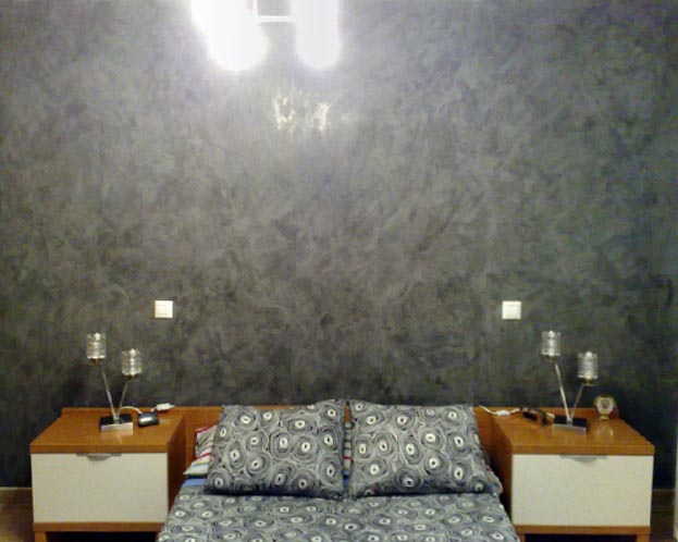 Un dormitorio con la pared del cabecero en estuco negro brillo